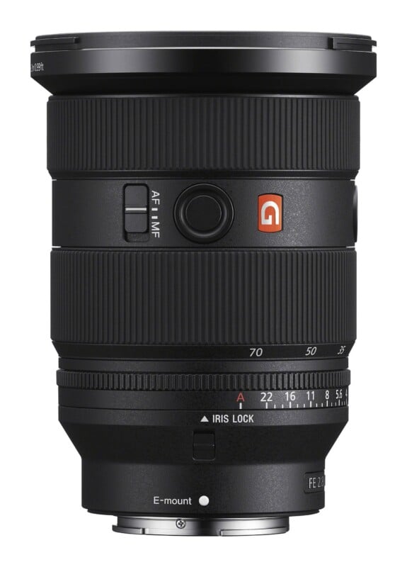 A black Sony G-Master camera lens with a zoom ring, focus ring, and aperture ring, viewed from the side against a white background.