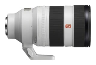 A white telephoto camera lens with black rubber grip rings and a tripod mount foot, viewed from the side against a white background.