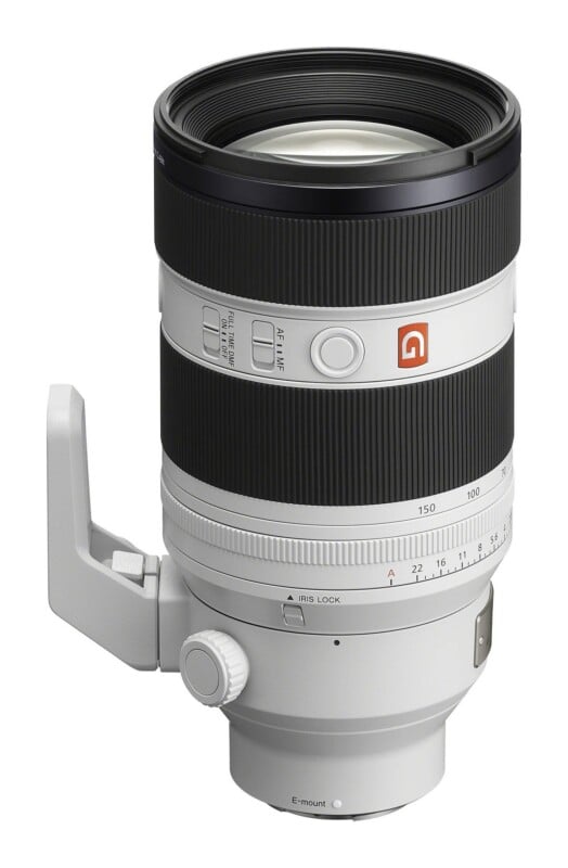 A white Sony G Master telephoto zoom lens for E-mount cameras, shown from a side angle with a tripod mount attached.