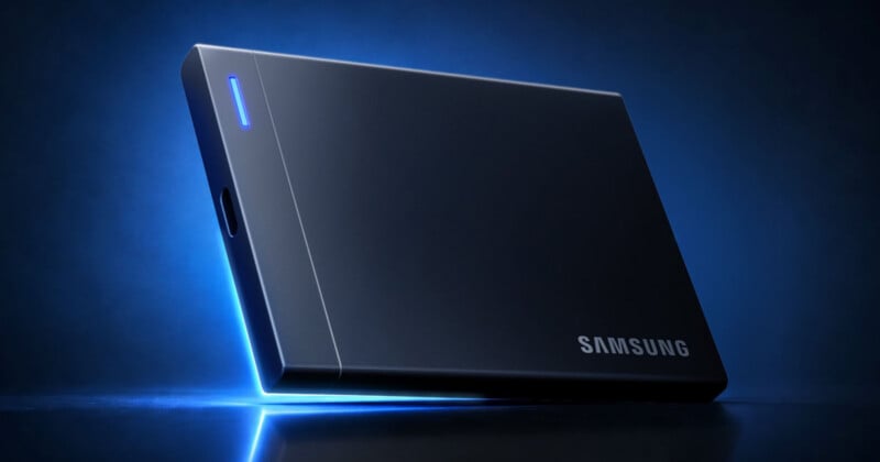 A black Samsung portable solid-state drive sits on a reflective surface against a dark blue background with a glowing blue light accent.