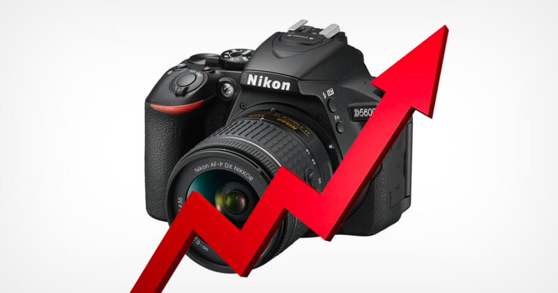 A Nikon D5600 camera is positioned behind a large, red, zigzagging upward-pointing arrow against a plain white background.