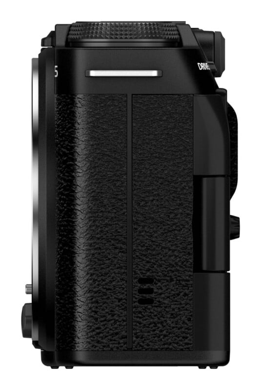 A side view of a black digital camera body featuring a textured grip, a silver strap lug, and a dial on the top edge.