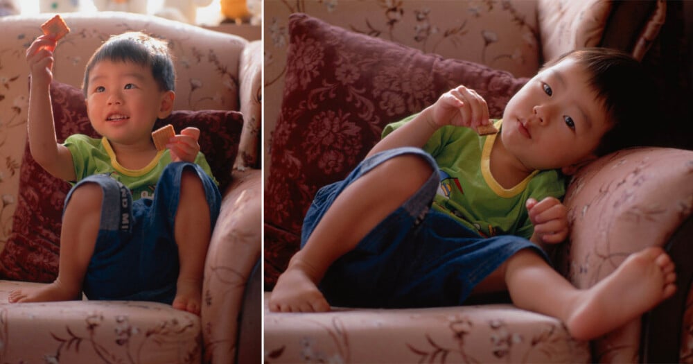 A young child in a green shirt and blue shorts sits on a patterned couch, holding and eating a small square cracker in two different poses.