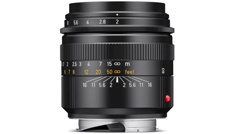 A black camera lens with white and yellow distance and aperture markings, featuring a red dot on the side and a metal mount at the base.