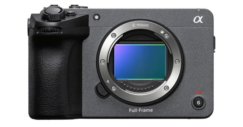 A front view of a gray, boxy digital cinema camera body with an E-mount lens opening, a visible full-frame sensor, a textured black grip, and a record button labeled with a 6.