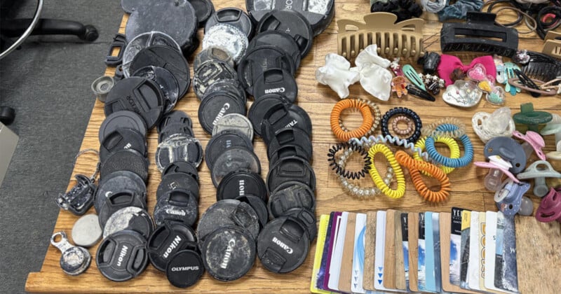A collection of camera lens caps, hair accessories, pacifiers, and plastic cards arranged on a wooden surface.