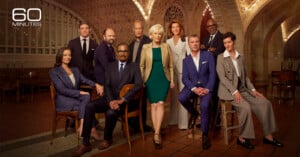 A group of ten people, five men and five women, pose for a formal portrait in a tiled, arched room with the 60 Minutes logo.