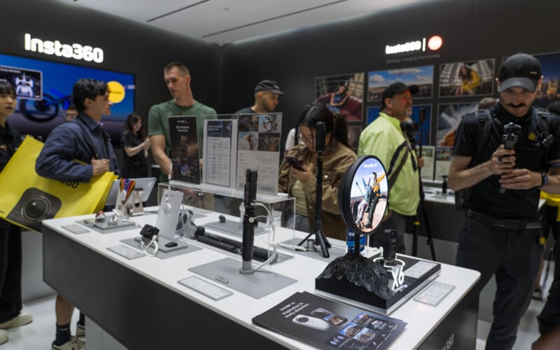 People browse a display of Insta360 cameras and accessories inside a brightly lit retail store.