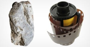 A grey, textured rock stands next to a roll of 35mm photographic film on a white background.