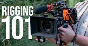 A person holds a professional cinema camera rig equipped with a matte box, a shotgun microphone, and an external monitor, with the text "RIGGING 101" overlaid on the left.