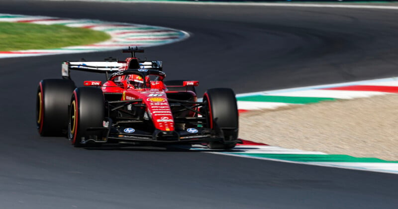 A red Ferrari Formula 1 race car with the number 16 drives around a curved track with red, white, and green curbing.