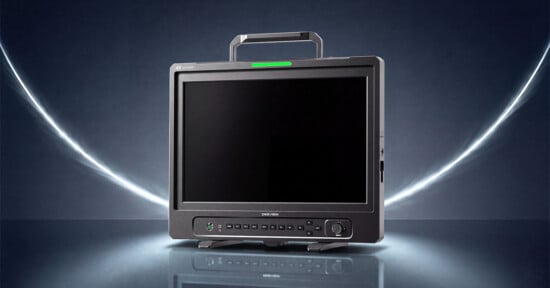 A Desview 4K 12G OLED monitor with a carrying handle sits on a reflective surface against a dark background with glowing light streaks.