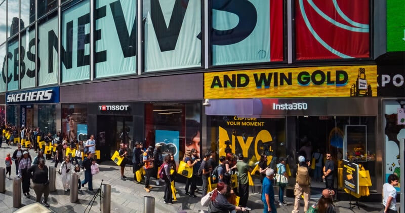 A crowd of people stands on a sidewalk in front of storefronts for Tissot and Insta360, with a large "AND WIN GOLD" sign above.