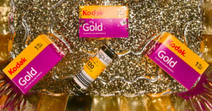 Two boxes of Kodak Gold 200 film and one roll of 120 film sit on a bed of gold glitter.