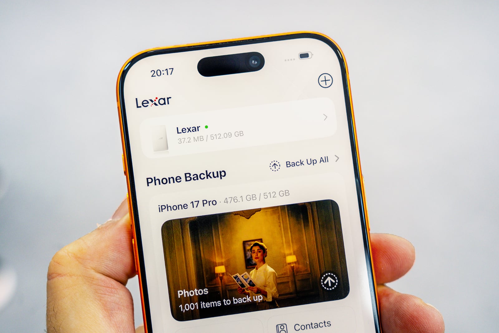 A hand holds a smartphone displaying a Lexar backup application interface, showing storage usage and a prompt to back up 1,001 photos.