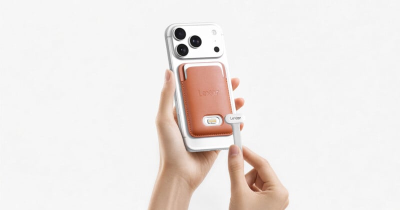 A person holds a white smartphone with a tan, leather-like magnetic card holder attached to the back, while their other hand holds a small white Lexar-branded connector near the device.