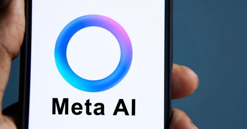 A hand holds a smartphone displaying the Meta AI logo, which consists of a colorful gradient ring above the text "Meta AI" on a white background.