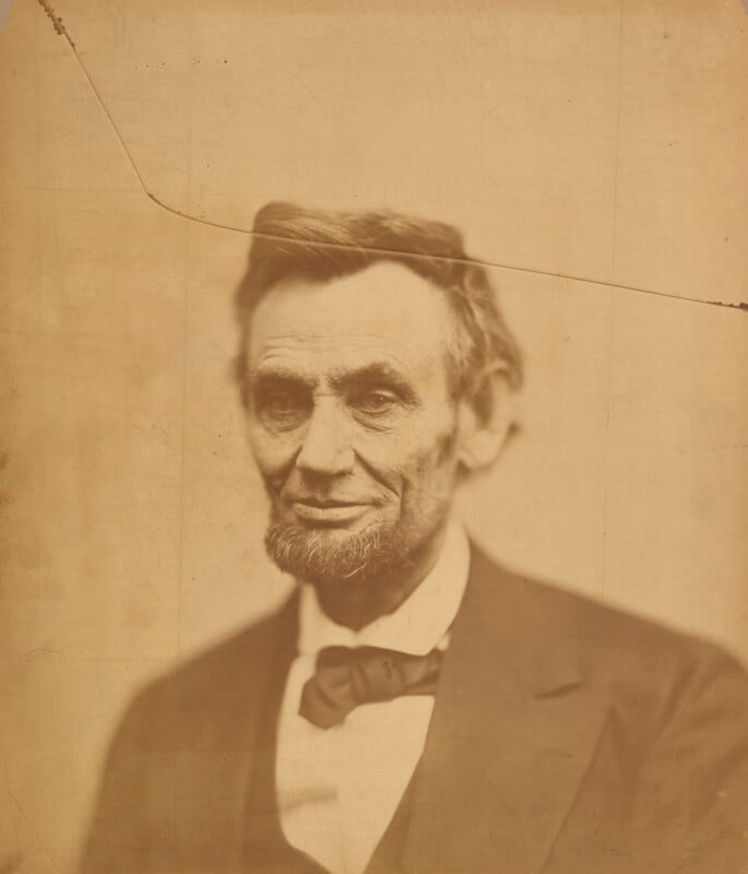A sepia-toned portrait of Abraham Lincoln, showing his head and shoulders, with a prominent diagonal crack across the top.