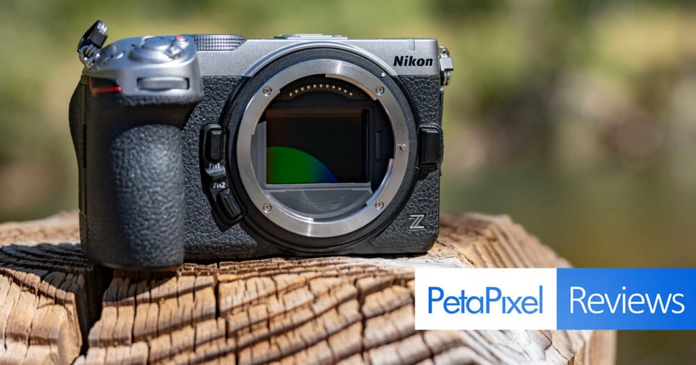 A silver and black Nikon Z mirrorless camera body sits on a weathered wooden stump, with a PetaPixel Reviews logo in the corner.