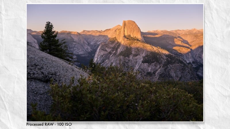 Half Dome in Yosemite National Park is illuminated by golden sunset light, viewed from a rocky, brush-covered foreground.