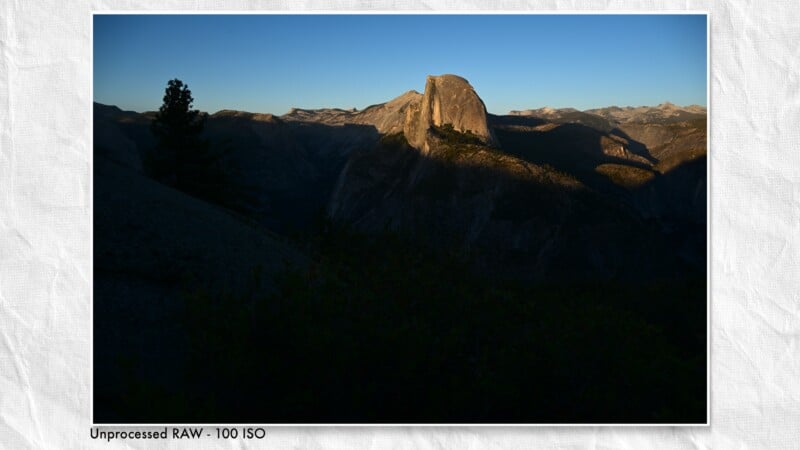 A high-contrast landscape view of Half Dome in Yosemite at sunrise, with deep shadows in the foreground and valley.