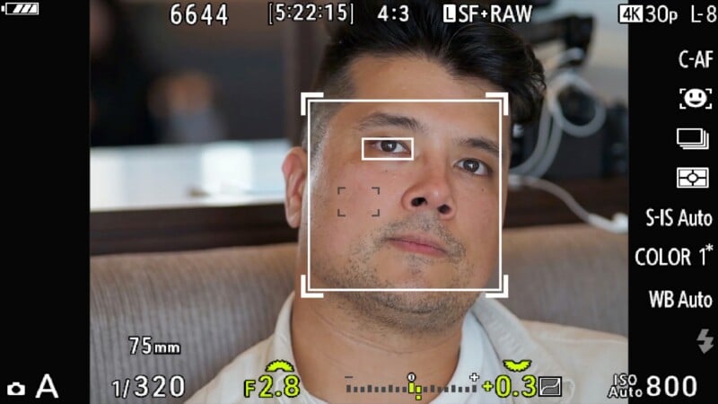 A digital camera viewfinder display shows a close-up portrait of a man with a focus box locked onto his eye and face.