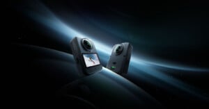 Two black action cameras with spherical lenses float against a dark, abstract background with blue light streaks.