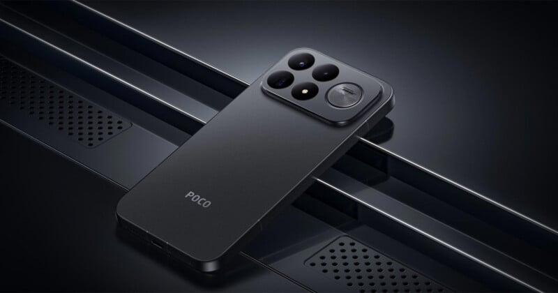 A matte black POCO smartphone rests at an angle on a dark, metallic surface with a perforated pattern, showcasing its rear camera module with multiple lenses and a circular accent.