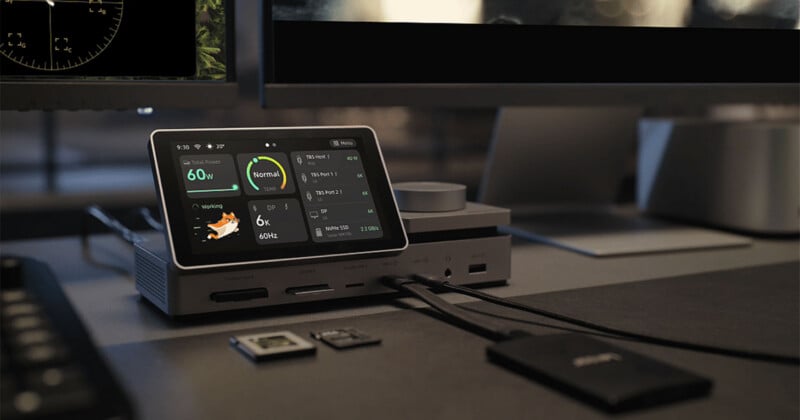 A docking station with a touchscreen display sits on a desk, showing system status, power usage, and connected devices.