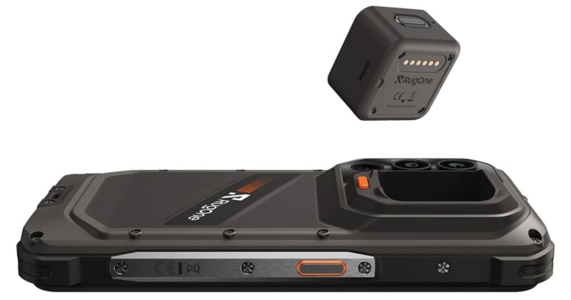 A rugged smartphone lying flat with a small, square, detachable camera module hovering above it.