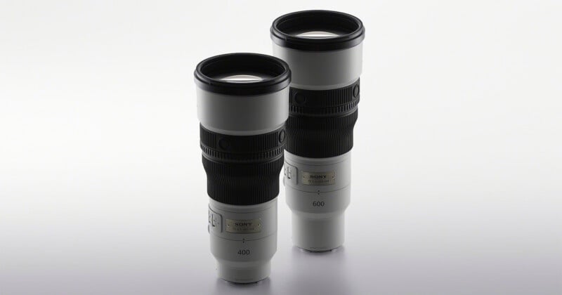 Two white Sony G Master telephoto lenses stand upright against a plain white background, with the 400mm lens in the foreground and the 600mm lens behind it.