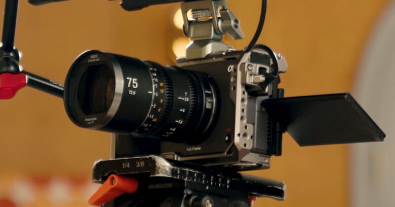 A professional cinema camera mounted on a tripod, featuring a 75mm T2.9 anamorphic lens and a side-mounted flip-out screen.