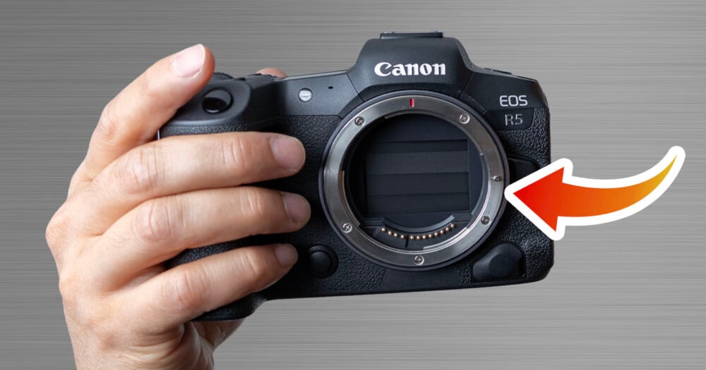 A hand holds a Canon EOS R5 camera body with a large red arrow pointing toward the lens mount.