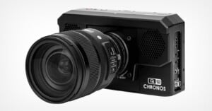 A black Chronos Q12 high-speed camera with a mounted Sigma lens, viewed from a front-side angle against a white background.
