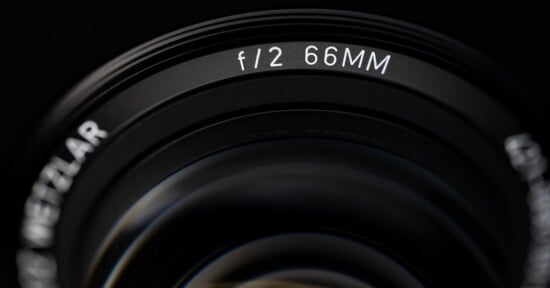 A close-up view of a camera lens barrel showing the text "f/2 66MM" and a partial view of the word "WETZLAR".