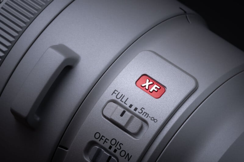 A close-up of a camera lens barrel featuring a red XF logo, a focus limiter switch set to FULL, and an Optical Image Stabilization (OIS) switch.