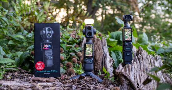 A black product box labeled "Xtra Muse 2 Pro" stands next to two handheld gimbal cameras on tripods, one with a small light attached, set against a background of green foliage and a tree stump.