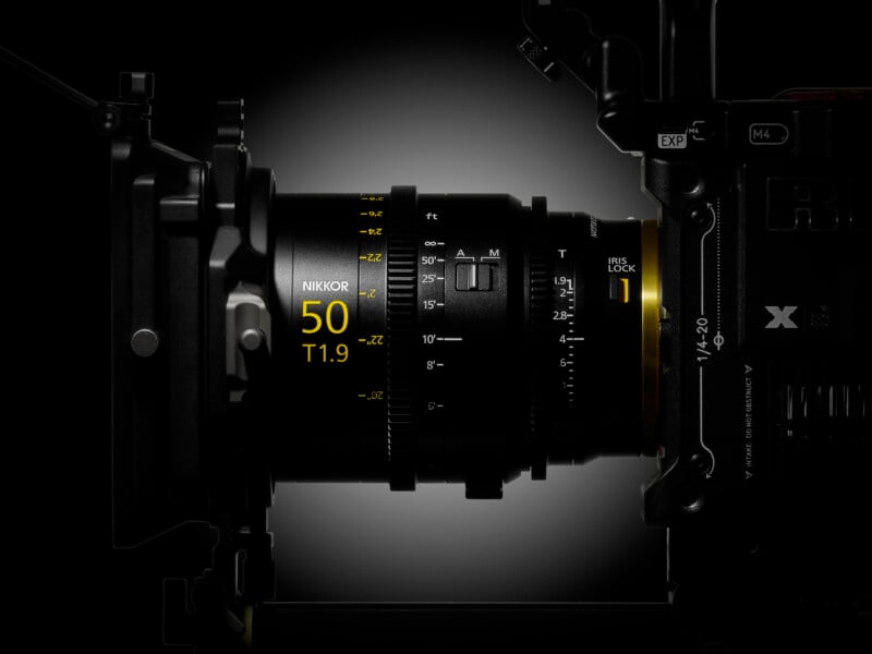A close-up side view of a cinema lens mounted on a camera body, featuring yellow text markings for "NIKKOR 50 T1.9" and focus distance settings.