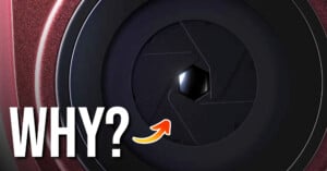 A close-up of a camera lens aperture with a hexagonal opening, featuring the word "WHY?" in large white letters and an orange arrow pointing toward the center.