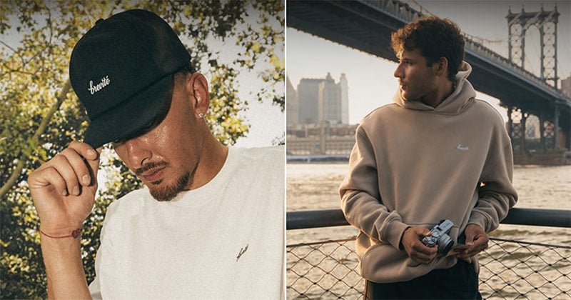 A split-screen view shows a man wearing a black baseball cap and white t-shirt on the left, and a man wearing a tan hoodie holding a camera on the right.