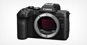 A black Canon EOS R8 Mark II mirrorless camera body shown from the front, featuring a lens mount, a textured grip, and a mode dial on top.