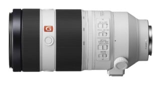 A white Sony FE 100-400mm f/4.5-5.6 GM OSS telephoto zoom lens shown from the side, featuring focus and stabilization switches.