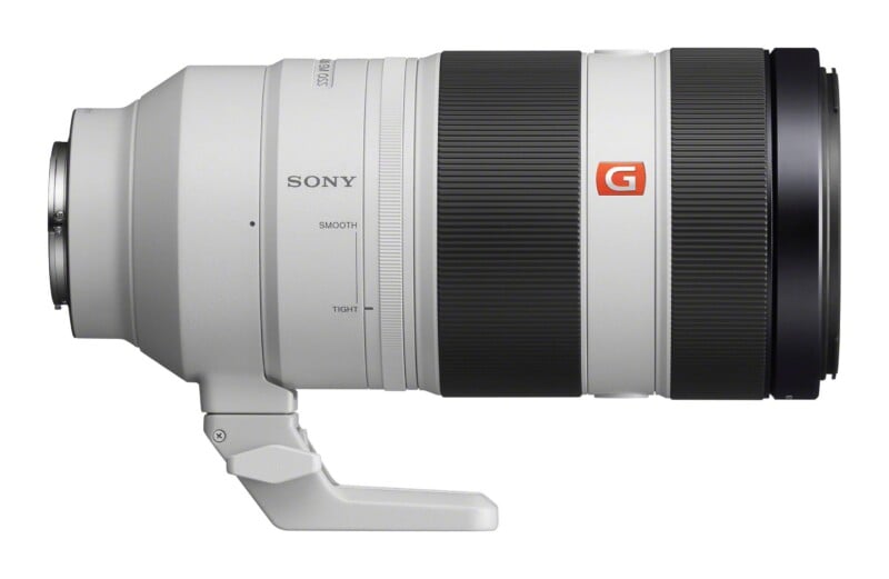 A white Sony G Master telephoto zoom lens shown from the side, featuring a black zoom ring, a focus ring, and a tripod mount at the base.