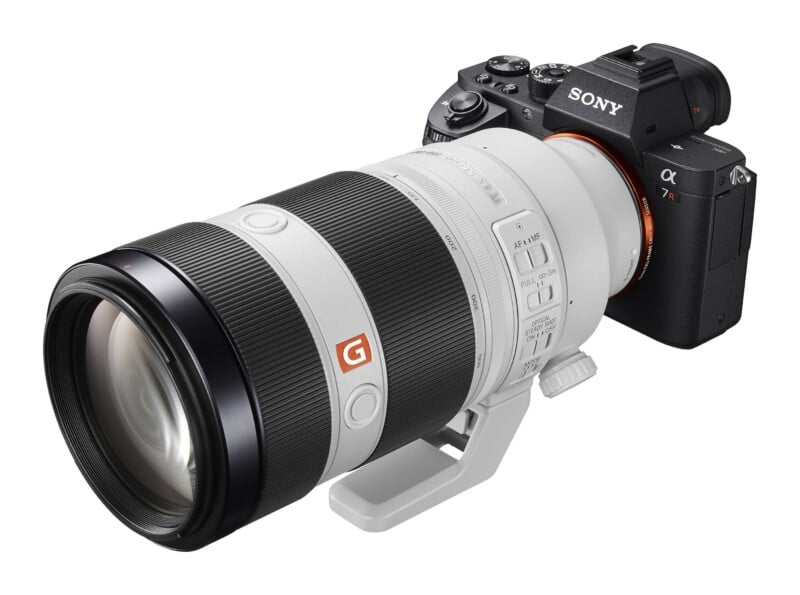 A Sony Alpha 7R mirrorless camera with a white telephoto zoom lens attached, viewed from a high angle against a white background.