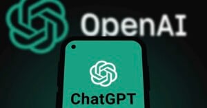 A smartphone screen displays the ChatGPT logo and text against a dark background featuring a large, blurred OpenAI logo.