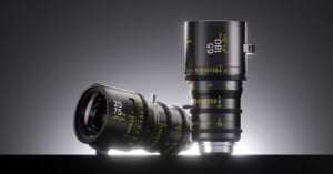 Two black cinema zoom lenses stand against a dark gray background, one lying horizontally and one standing vertically, both featuring yellow text markings.