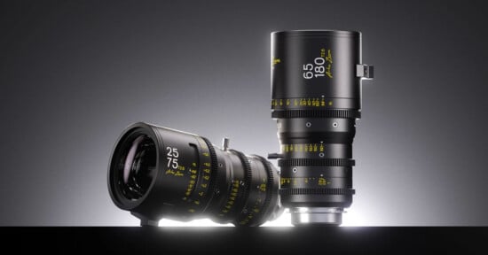 Two black cinema zoom lenses stand against a dark gray background, one lying horizontally and one standing vertically, both featuring yellow text markings.