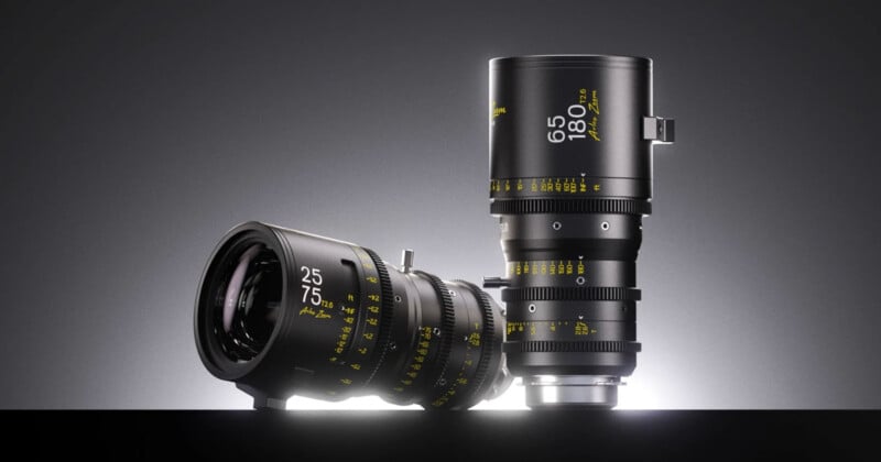 Two black cinema zoom lenses stand against a dark gray background, one lying horizontally and one standing vertically, both featuring yellow text markings.