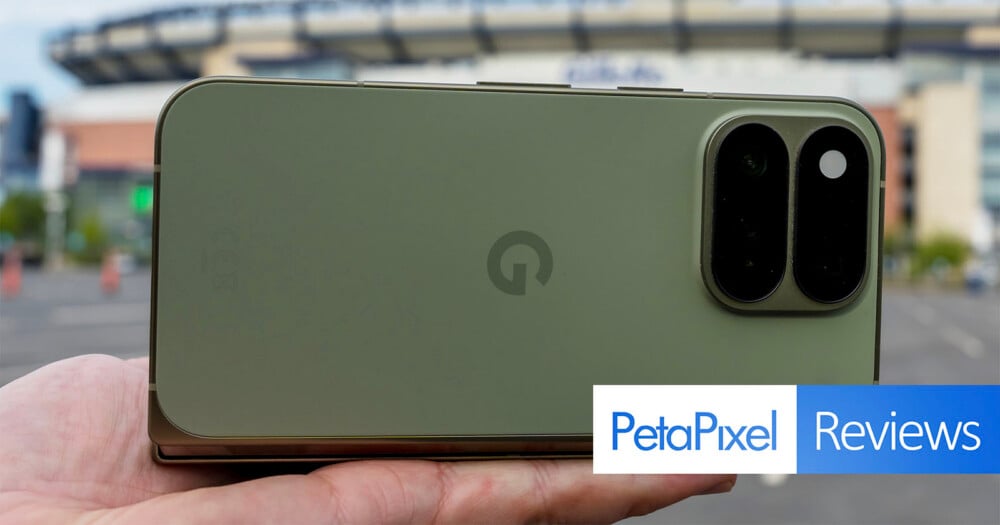 A hand holds a green smartphone with a dual-lens camera module on the back, with a PetaPixel Reviews logo in the corner.