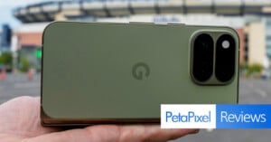 A hand holds a green smartphone with a dual-lens camera module on the back, with a PetaPixel Reviews logo in the corner.